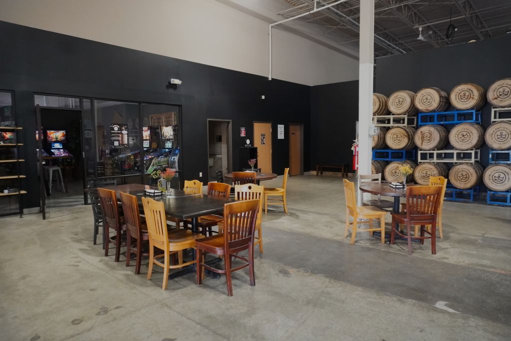 This image shows the barrels, bathrooms, and some of the tables at the back of Noble Cut Distillery's Bar